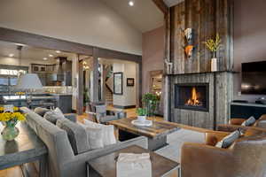 Living room featuring hanging lights, light wood-style floors, vaulted ceiling, and a fireplace