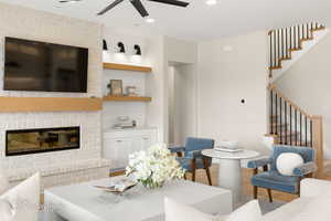 Living room with wood finished floors, a ceiling fan, a brick fireplace, and recessed lighting