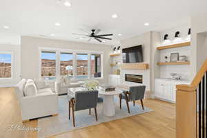 Living room with a ceiling fan, light wood-type flooring, recessed lighting, and a brick fireplace