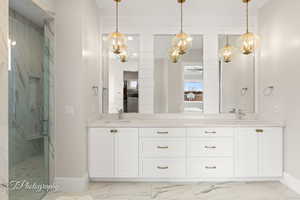 Bathroom with double vanity, a marble finish shower, ceiling fan, and light marble finish floors