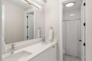 Full bath featuring curtained shower, double vanity, and light tile patterned flooring