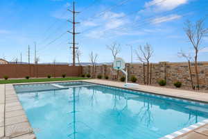 Combined pool / hot tub with a fenced backyard and a patio