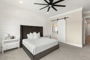 Carpeted bedroom featuring a barn door, ceiling fan, recessed lighting, crown molding, and ensuite bathroom