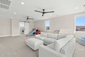 Living room with a barn door, light carpet, a ceiling fan, and recessed lighting