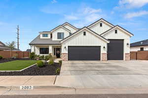 Modern inspired farmhouse featuring board and batten siding, an attached garage, driveway, covered porch, and brick siding