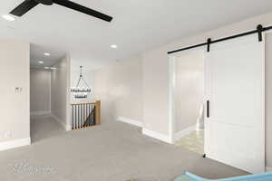 Unfurnished room featuring a barn door, a ceiling fan, light carpet, and a chandelier
