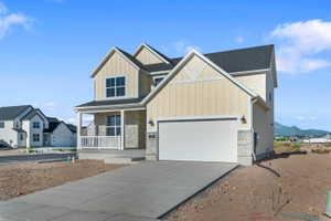 Modern two-story residence featuring a covered porch, attached two-car garage, and a concrete driveway