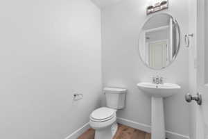 White pedestal sink with chrome faucet, oval mirror, and contemporary light fixture