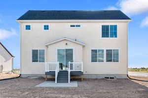 Rear exterior featuring a covered patio with sliding glass door access, white railings, and steps to grade