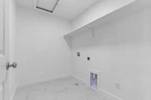 Dedicated utility room featuring a large wall shelf, washer/dryer hookups, and a clean white color palette
