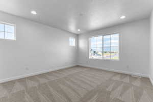 Spacious room featuring neutral carpeting, recessed lighting, and multiple windows providing ample natural light