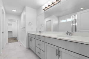 Bathroom featuring a double vanity with light gray cabinetry, chrome hardware, and white countertops