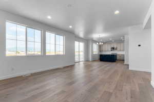 Bright open-concept living area featuring wood-finish flooring, recessed lighting, and large grid-pattern windows