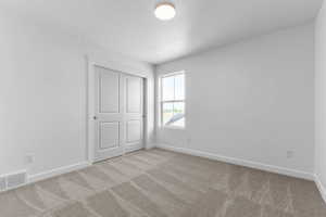 Neutral-toned carpeting enhances this bright room featuring a window and white trim