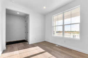 Light wood-finish flooring and bright white walls define this space, featuring a prominent multi-pane window