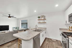 Kitchen with a peninsula, a kitchen breakfast bar, white cabinetry, open floor plan, and recessed lighting