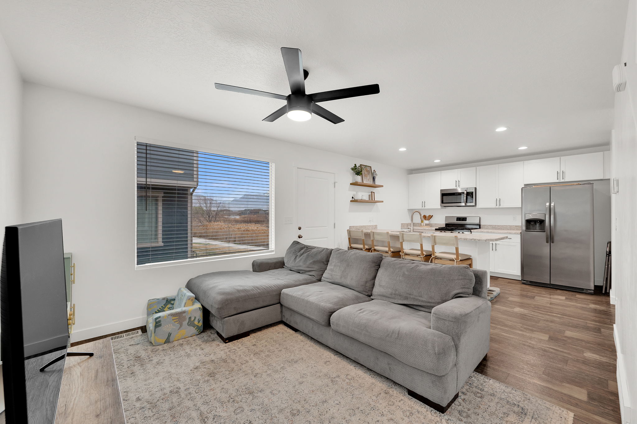 Living area with a ceiling fan, light wood finished floors, and recessed lighting