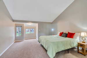 Bedroom with light carpet and vaulted ceiling