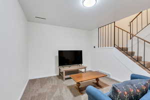 Living area with light colored carpet and stairway