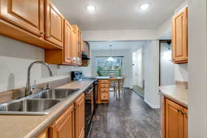 Kitchen with light countertops, black appliances, and decorative light fixtures