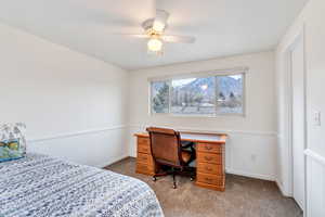 Bedroom featuring wainscoting, dark carpet, and ceiling fan