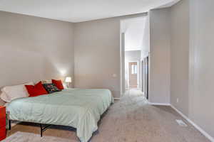 Bedroom featuring light carpet and a high ceiling