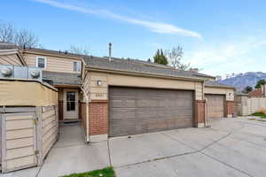 View of front of property with brick siding, a shingled roof, concrete driveway, a gate, and a mountain view