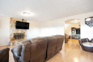 Living room with arched walkways, light wood-style floors, and a fireplace