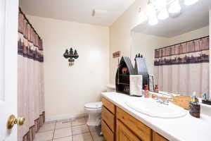 Full bath featuring a shower with shower curtain, vanity, and light tile patterned flooring