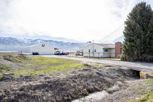 View of yard with a mountain view, an outdoor structure, a pole building, and driveway
