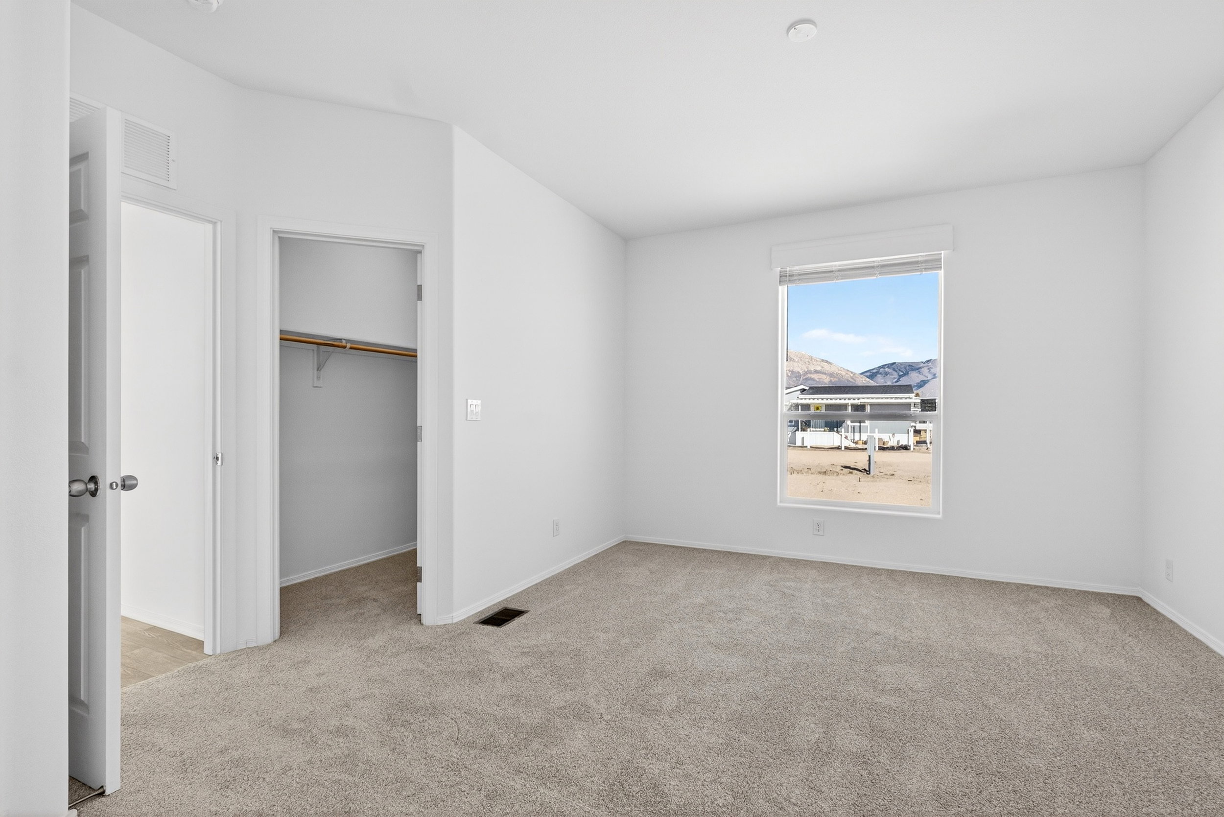 Unfurnished bedroom with a spacious closet, light colored carpet, and a mountain view