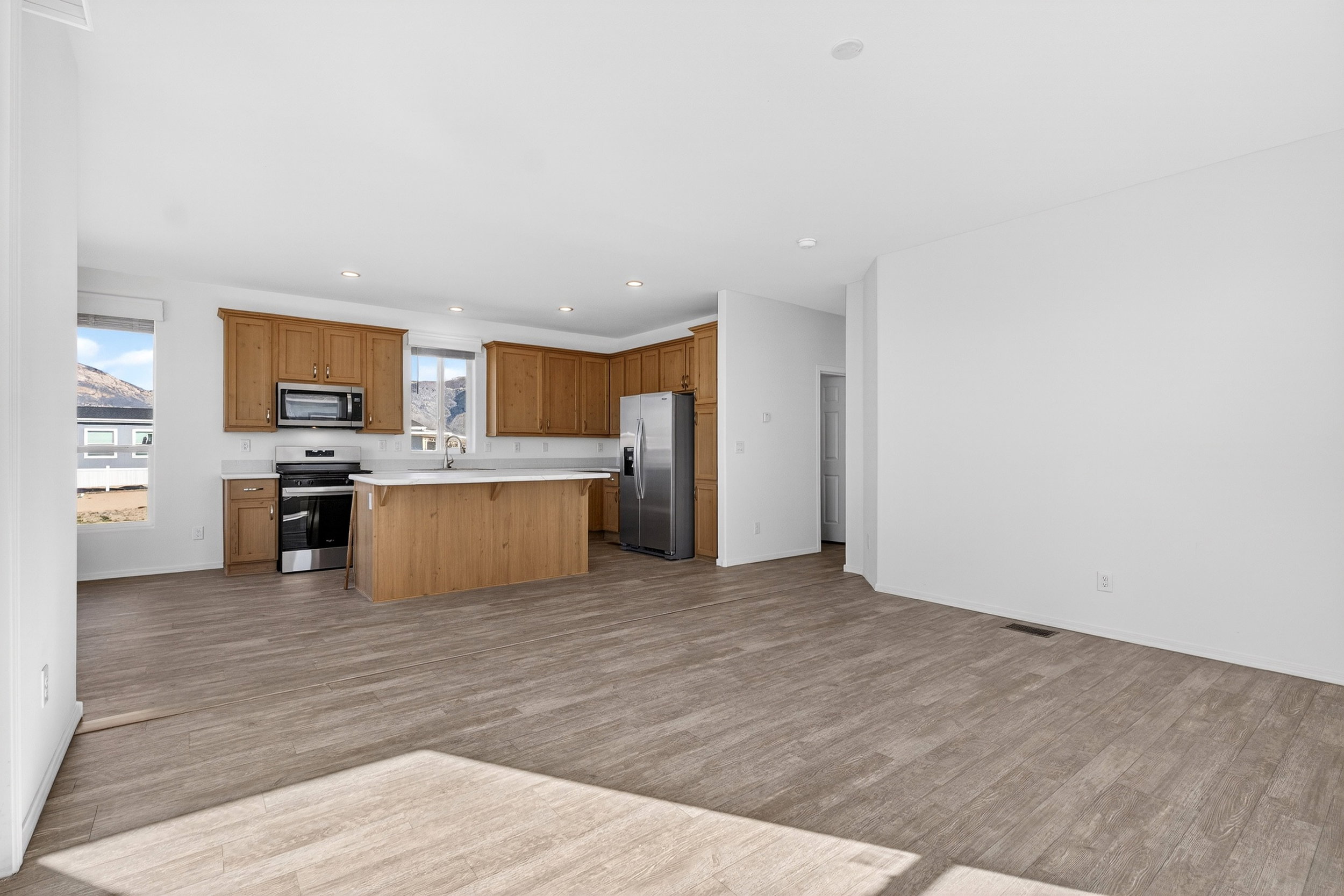 Kitchen featuring stainless steel appliances, light countertops, open floor plan, a kitchen island, and a kitchen bar