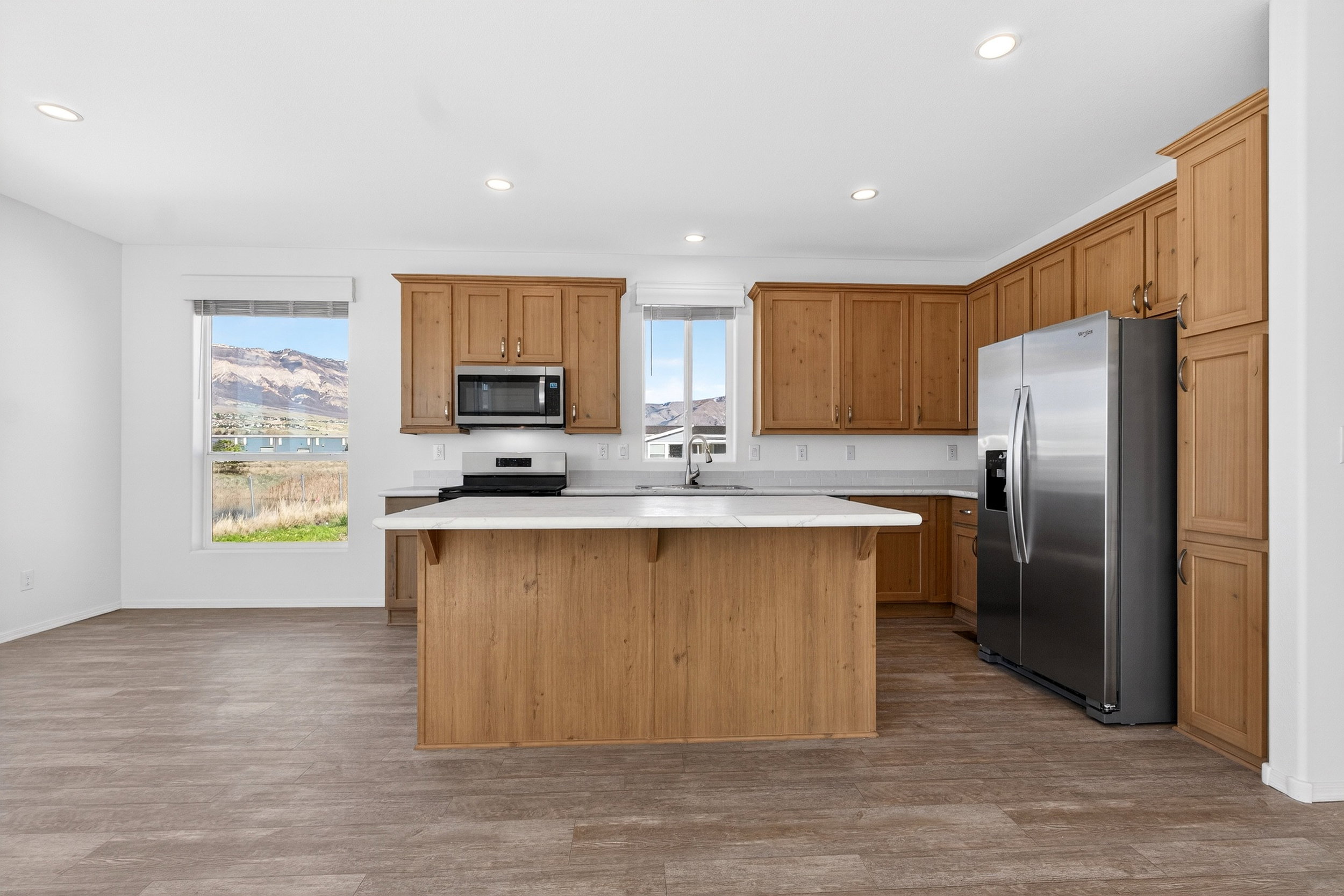 Kitchen featuring stainless steel appliances, a breakfast bar, a center island, dark wood-style flooring, and recessed lighting