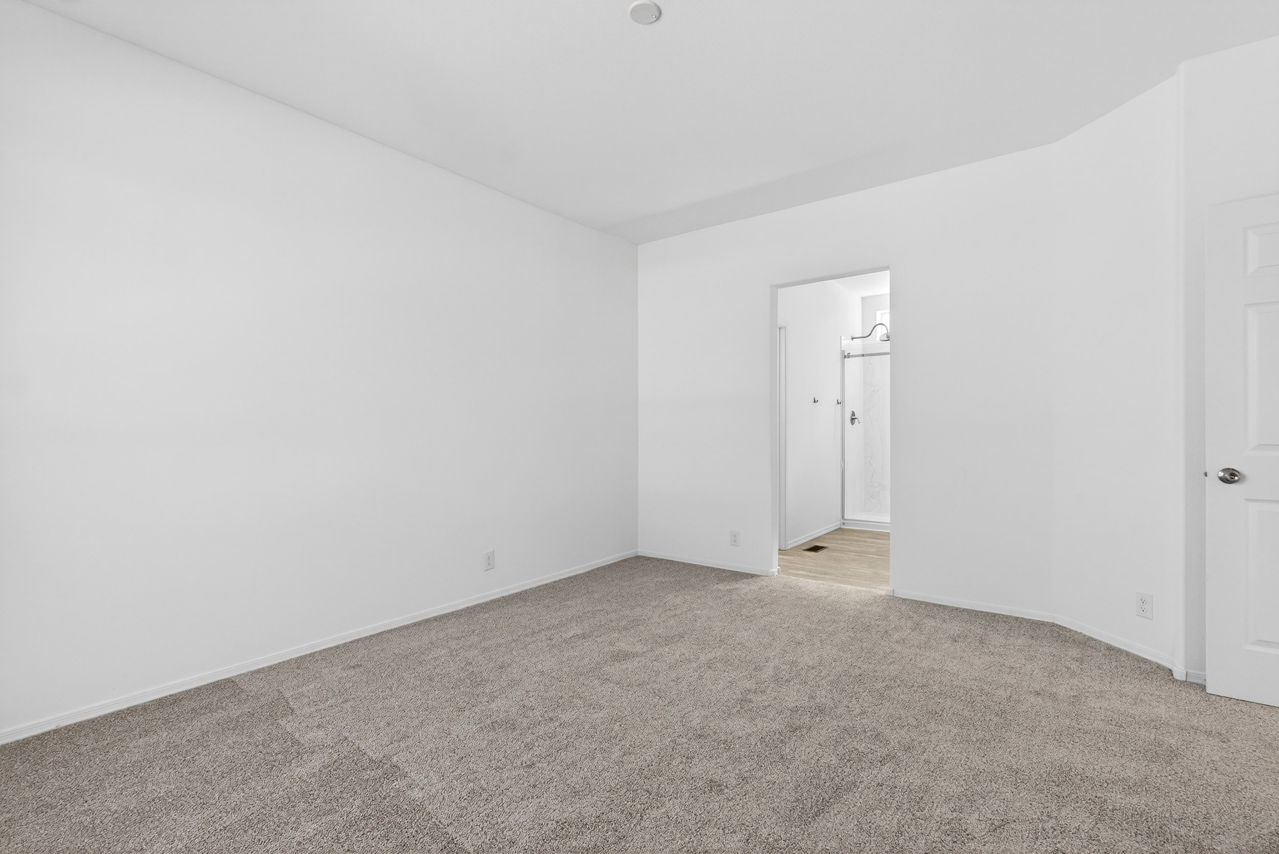 Unfurnished bedroom with light carpet and ensuite bathroom
