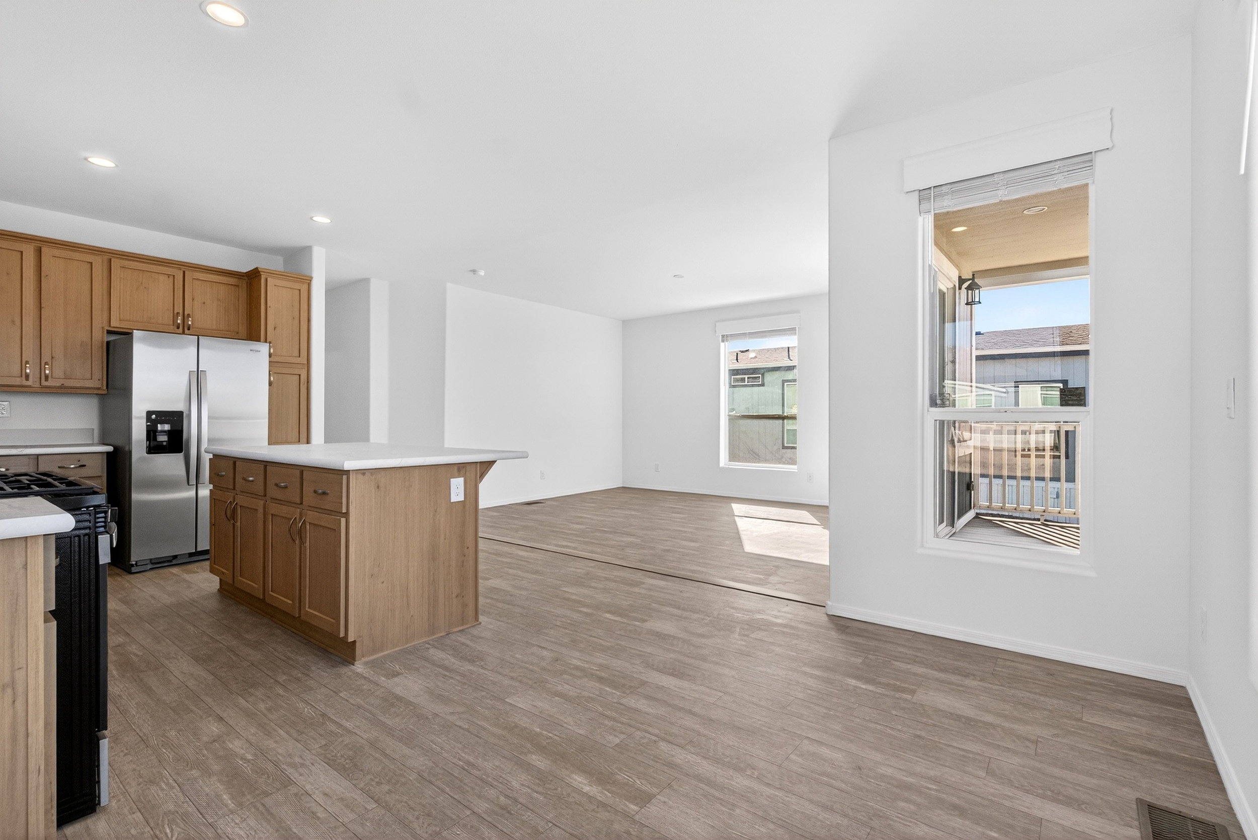 Kitchen featuring stainless steel fridge, light countertops, freestanding range oven, a center island, and open floor plan