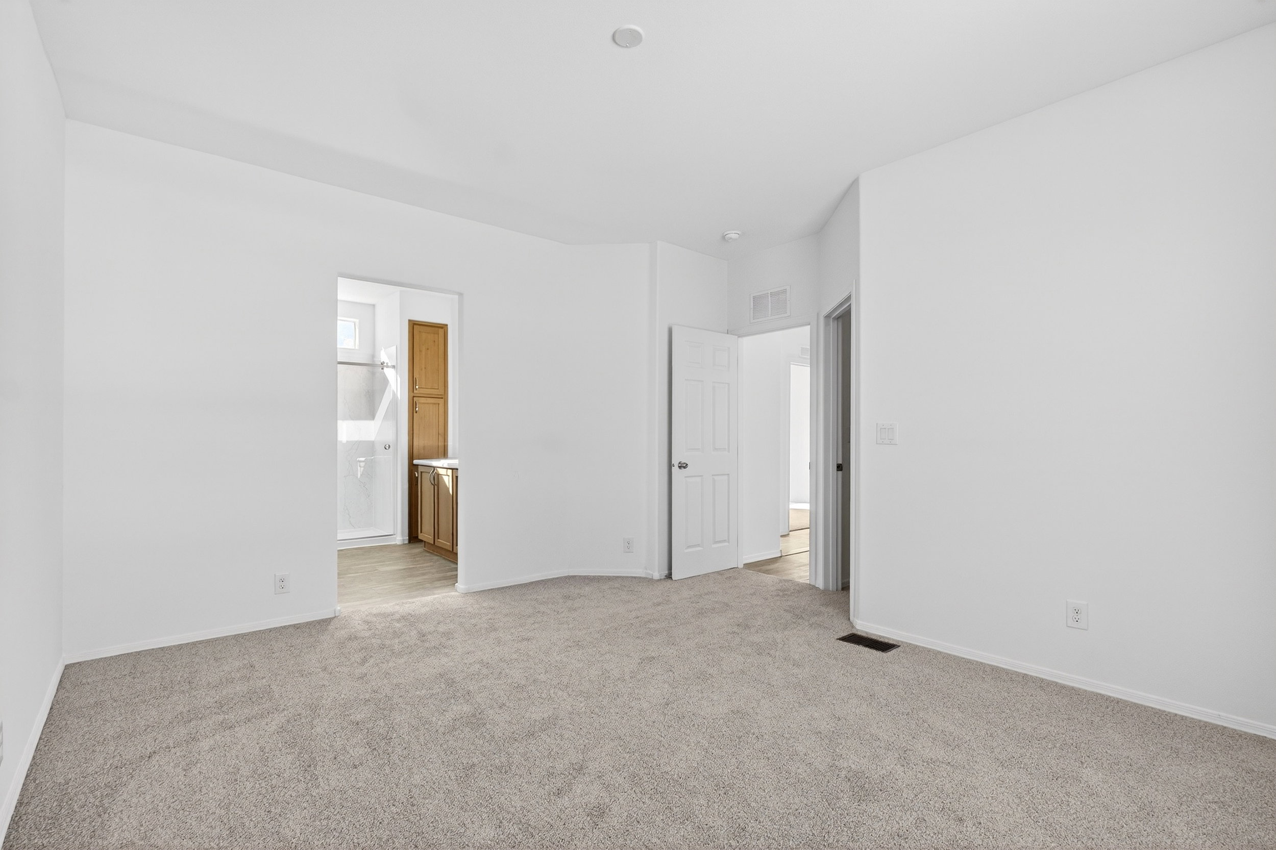 Unfurnished bedroom with connected bathroom and light carpet