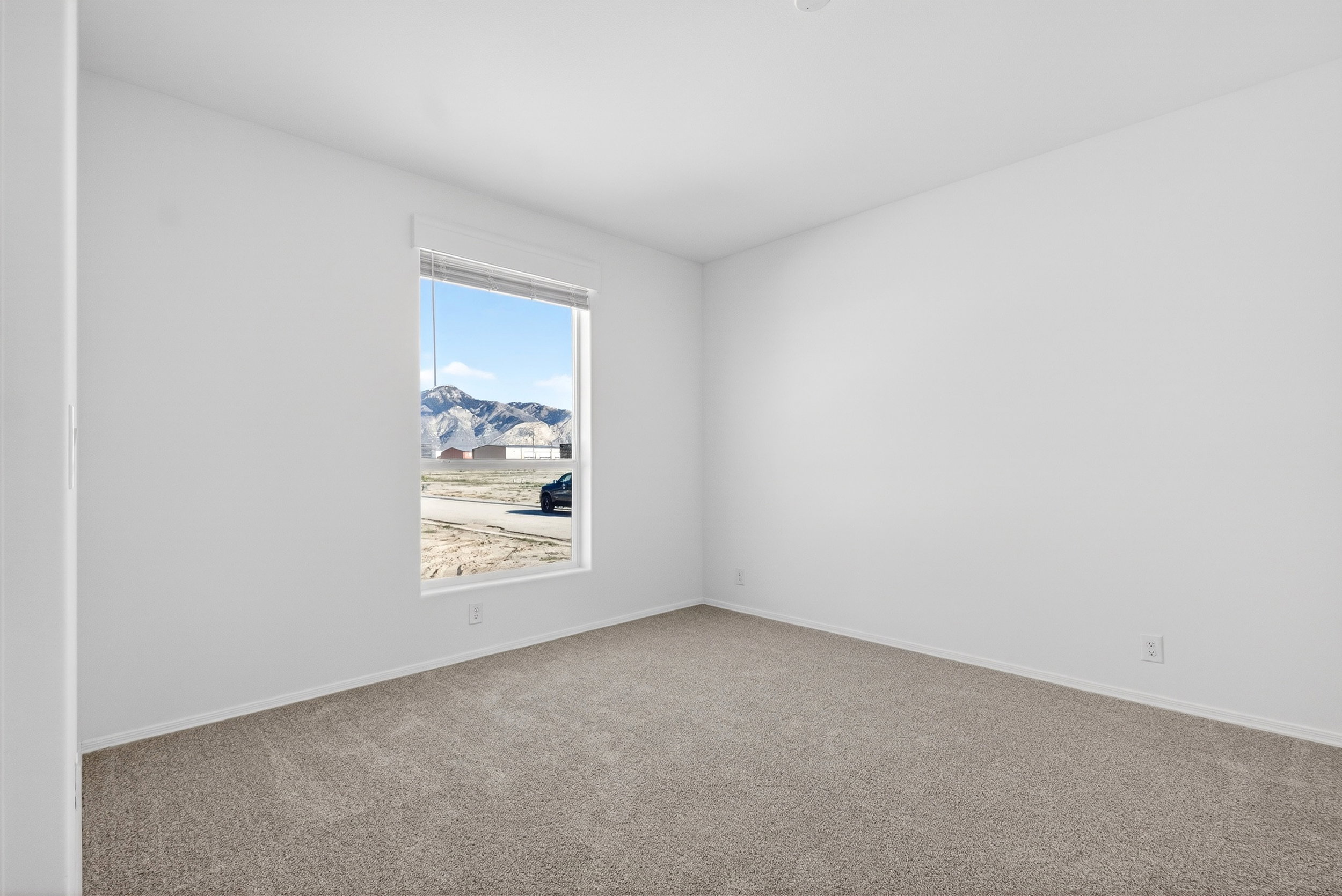Carpeted empty room featuring baseboards and a mountain view