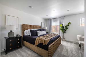 Bedroom featuring light colored carpet and a textured ceiling