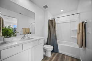 Bathroom featuring dark wood-style flooring, vanity, and shower / bathtub combination with curtain