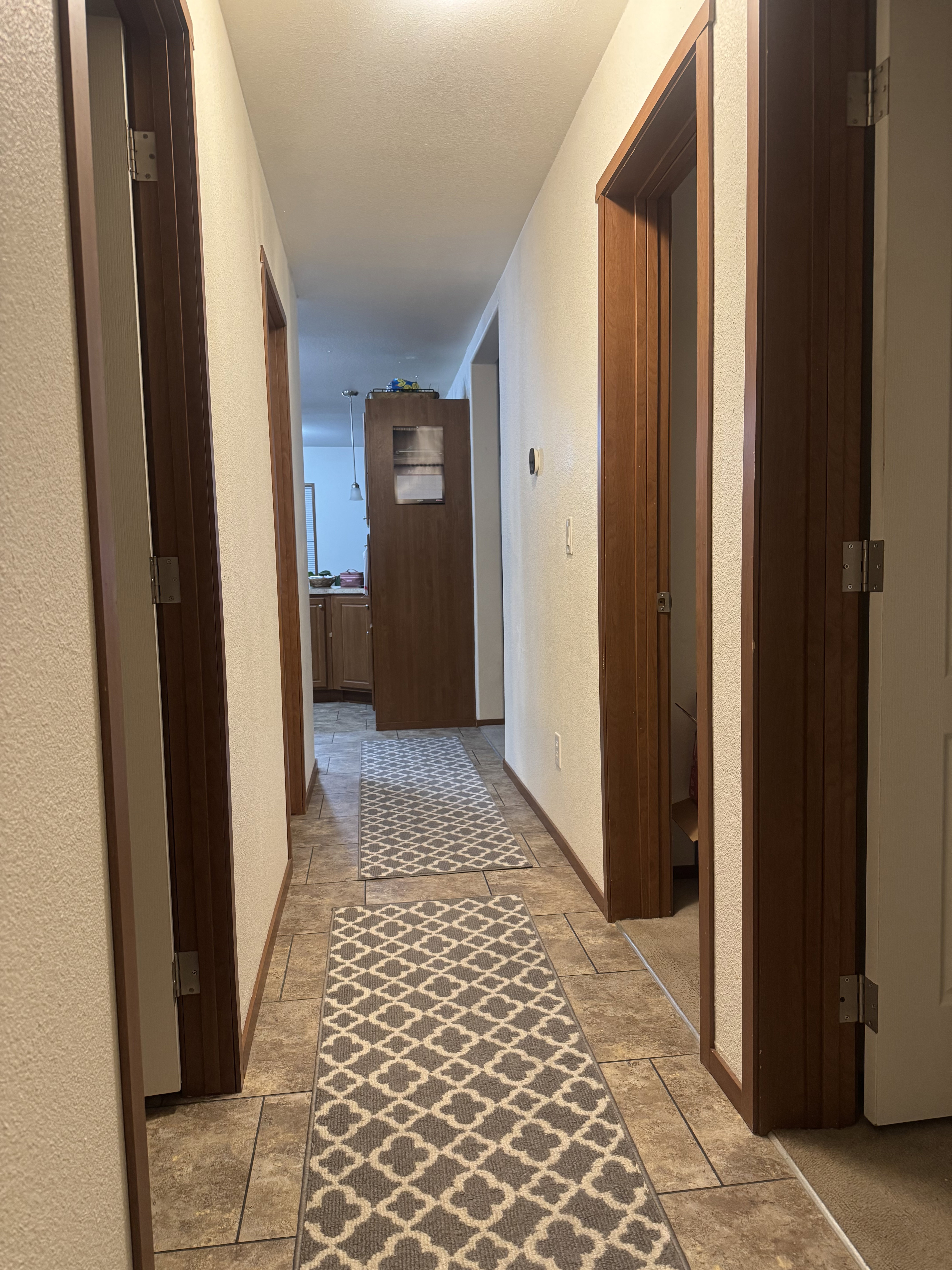 Hall featuring a textured wall and light stone finish floors