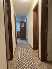 Hall featuring a textured wall and light stone finish floors