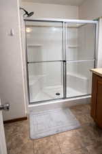 Full bath featuring vanity, a shower stall, and a textured wall