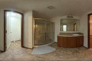 Bathroom featuring vanity, a stall shower, a barrel ceiling, and light tile patterned floors