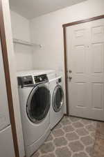 Laundry room featuring washer and dryer and a textured wall
