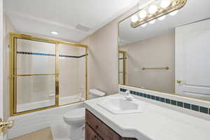 Bathroom featuring vanity and shower / bath combination with glass door