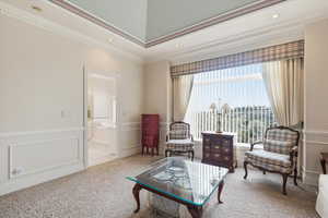 Sitting room featuring wallpapered walls, wainscoting, a decorative wall, and light carpet