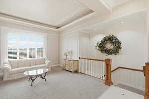 Living area featuring carpet, a tray ceiling, and ornamental molding