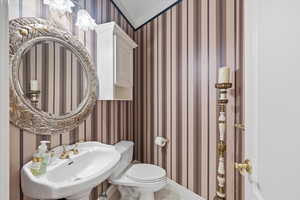Half bathroom featuring wallpapered walls and light tile patterned floors