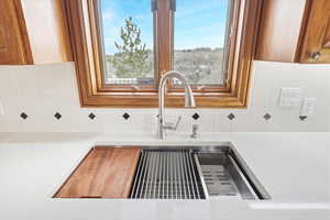 Kitchen view of wood finish cabinets, tasteful backsplash, and light stone counters