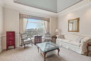 Carpeted living area featuring a wainscoted wall, a decorative wall, crown molding, and wallpapered walls